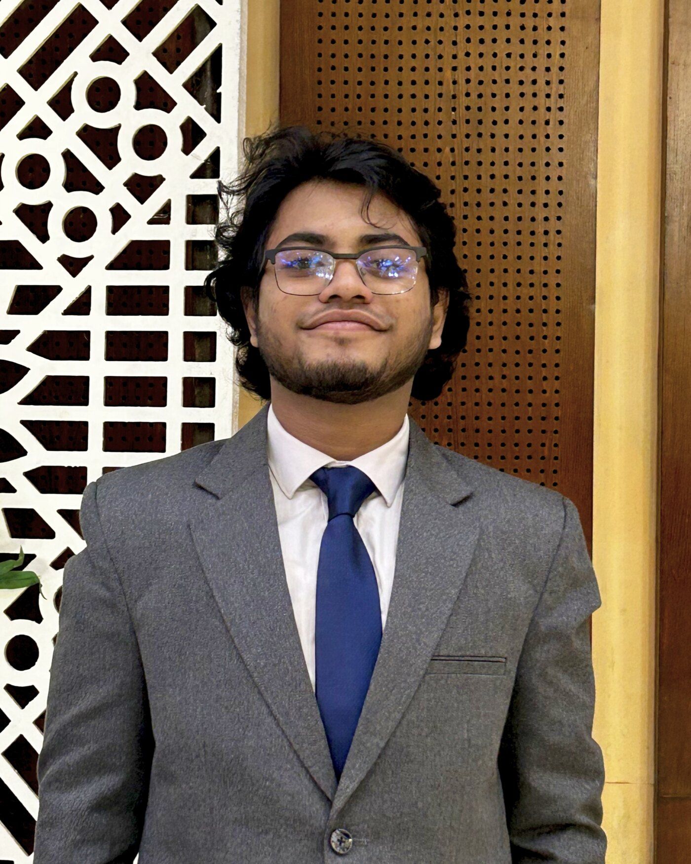Kabya Mithun Saha, smiling, in a grey suit with a blue tie.
